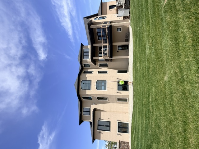 Technician cleaning the upper windows of a large residential home with a water-fed pole